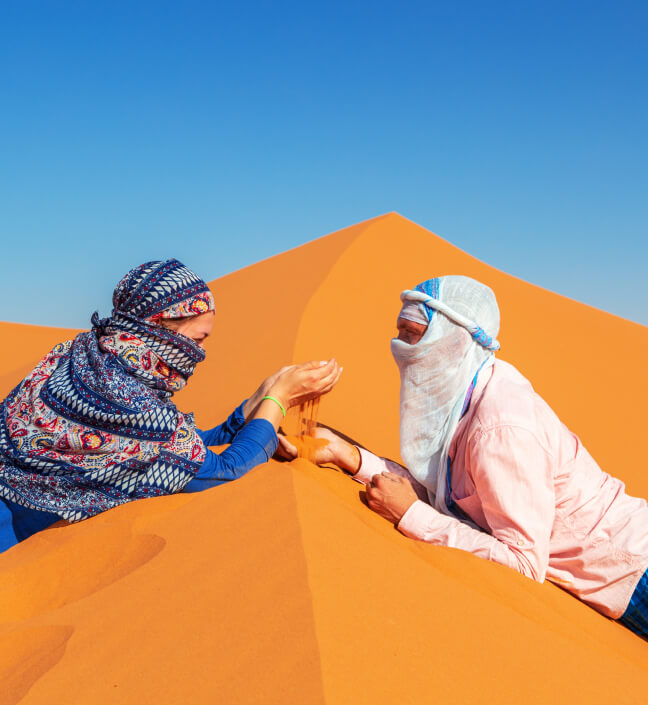 Couple sitting together on orange desert dunes